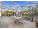 Covered and screened outdoor seating with stylish table and chairs next to a pristine pool at 4509 Golden Gate Cv, Bradenton, FL 34211