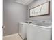 Functional laundry room with modern white washer and dryer, complemented by a decorative wall hanging at 5914 Falconwood Pl, Lithia, FL 33547