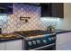 Close-up of the kitchen stove featuring stainless steel accents, a sleek black design and tile backsplash at 6536 Simone Shores Cir, Apollo Beach, FL 33572