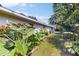 Lush backyard with vibrant plants, a manicured lawn, and the side of the home with screened lanai at 2666 Red Oak Ct, Clearwater, FL 33761