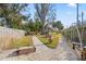 Lush backyard featuring mature trees, a gravel walkway, and a fire pit, creating a private retreat at 10098 Oaks Ln, Seminole, FL 33772