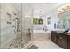 Bright bathroom with a large tub, glass shower, and large vanity at 10098 Oaks Ln, Seminole, FL 33772