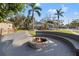 Inviting backyard featuring a stone fire pit with built-in seating, perfect for outdoor entertaining and relaxation at 10098 Oaks Ln, Seminole, FL 33772