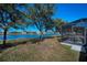 A view of the backyard featuring lush landscaping with a lake view and screened lanai at 12141 Arron Ter, Trinity, FL 34655