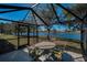 Screened lanai with outdoor dining area overlooks the lake and lush backyard at 12141 Arron Ter, Trinity, FL 34655