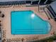 High angle on large rectangular pool with sun glinting off water, surrounded by lounge chairs on brick patio at 12141 Arron Ter, Trinity, FL 34655