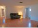 View of the main living room with wood-look floors, neutral walls, and a black reclining sofa at 1436 Rose St, Clearwater, FL 33756