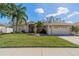 Charming single-story home featuring a well-manicured lawn, palm trees, and a two-car garage at 1509 Ventana Dr, Sun City Center, FL 33573