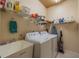 Bright laundry room with a utility sink, white washer and dryer, and ample storage shelves at 1509 Ventana Dr, Sun City Center, FL 33573