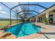 A serene screened-in pool area with a waterfall, mature landscaping, and brick paver deck at 1509 Ventana Dr, Sun City Center, FL 33573