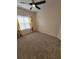 A bedroom featuring neutral carpeting, a ceiling fan, and a bright window at 21031 Sunpoint Way # 202, Lutz, FL 33558