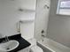 Bright bathroom featuring a tub with marble-like tiling, a sleek vanity, and floating shelves at 3110 N Massachusetts Ave, Tampa, FL 33603