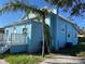 Side view of the light blue home with a metal roof and lush landscaping at 3110 N Massachusetts Ave, Tampa, FL 33603