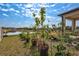 Landscaped backyard with row of potted plants, fruit trees, and view of pond at 3192 King Fern Dr, Wimauma, FL 33598