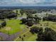 Picturesque aerial view of golf course with mature trees and water features on a partly cloudy day at 37027 Lakota Ct, Zephyrhills, FL 33542