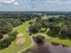 Beautiful aerial view of golf course with mature trees and water features on a partly cloudy day at 37027 Lakota Ct, Zephyrhills, FL 33542