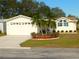 Charming single-story home with a well-manicured front lawn, palm trees, and attached two-car garage at 37027 Lakota Ct, Zephyrhills, FL 33542