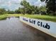 View of the Betmar Golf Club sign by the water, surrounded by lush greenery at 37027 Lakota Ct, Zephyrhills, FL 33542