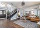 Open-concept living room with hardwood floors, a staircase, leather sofa, and seamless connection to kitchen at 5292 Kernwood Ct, Palm Harbor, FL 34685