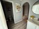 This bathroom showcases an arched doorway, decorative sunflower art, a vanity, and stylish gray wood-look flooring at 6113 Freeport Dr, Spring Hill, FL 34606