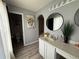 Bathroom featuring an arched doorway, a vanity, round mirror, modern lighting, decorative sunflower art, and wood-look flooring at 6113 Freeport Dr, Spring Hill, FL 34606