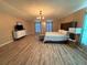 Spacious main bedroom with modern decor, wood-look floors, a stylish bed, and an elegant chandelier at 6113 Freeport Dr, Spring Hill, FL 34606