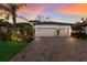 Charming single-story home featuring a three-car garage and lush landscaping at sunset at 706 Acacia Ct, Bradenton, FL 34212