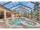 Relaxing screened-in pool and spa with convenient handrails, surrounded by covered patio and lush greenery at 8510 Kentucky Derby Dr, Odessa, FL 33556