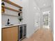 Hallway with built in wine fridge, wood cabinets, shelves, and view into an adjacent bathroom at 910 W West St, Tampa, FL 33602