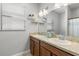 Bathroom with dual sinks, tan countertops, and a mirror with decorative shelving for accessories at 10063 Celtic Ash Dr, Ruskin, FL 33573