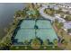 Aerial view of two tennis courts and a basketball court next to a lake in a residential community at 10063 Celtic Ash Dr, Ruskin, FL 33573