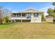 Home's back exterior view with screened porch, sliding doors, and landscaped yard at 1007 Lake Avoca Dr, Tarpon Springs, FL 34689