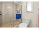 Bathroom shower featuring glass doors, neutral tile, shower head and adjacent toilet at 1007 Lake Avoca Dr, Tarpon Springs, FL 34689