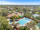 Stunning aerial view of community pool, hot tub, tennis and shuffleboard courts surrounded by mature trees and landscaping at 1007 Lake Avoca Dr, Tarpon Springs, FL 34689