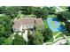 Overhead view of a townhome complex with tennis court and pond in a lush, green community at 102 Brent Cir, Oldsmar, FL 34677