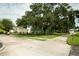 Street view in a gated community with mature trees, landscaping, and a glimpse of a tennis court at 102 Brent Cir, Oldsmar, FL 34677