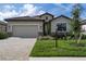 Charming single-story home showcasing stone accents, manicured lawn, and a brick-paved driveway leading to a two-car garage at 11393 Pinot Dr, Venice, FL 34293