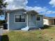 Charming single-story home featuring a covered entry, light-blue siding, and lush, green landscaping at 14413 Birch St, Hudson, FL 34667