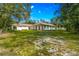 Wide view of a single-story white home surrounded by healthy green grass and shade trees at 17630 Brown Rd, Odessa, FL 33556