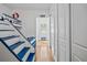 Bright hallway with blue and white nautical theme steps leading to a playful loft and light hardwood floors at 17630 Brown Rd, Odessa, FL 33556