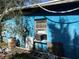 Rear exterior of the blue home showing unkempt lawn, block construction, and an AC unit at 1911 E Noel St, Tampa, FL 33610