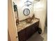 Bathroom sink with brown cabinets, a decorative round mirror, and tan countertop at 2172 University S Dr, Clearwater, FL 33764