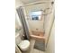 View of the bathroom with white tile walls, pink tub, toilet, and a window above the tub at 2172 University S Dr, Clearwater, FL 33764