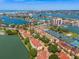 Aerial view of condo complex showcasing waterfront access, community pool, tennis courts, and lush landscaping at 440 Sandy Hook Rd, Treasure Island, FL 33706