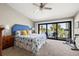 Bright bedroom featuring a ceiling fan, plush carpet, and a balcony with tropical views at 440 Sandy Hook Rd, Treasure Island, FL 33706