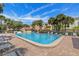 Community pool with ample lounge chairs surrounded by lush landscaping and sunny skies at 440 Sandy Hook Rd, Treasure Island, FL 33706