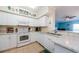 Well-lit kitchen featuring white cabinets and a view to the living room at 4516 Seagull Dr # 405, New Port Richey, FL 34652