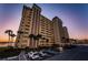 Stunning exterior view of a waterfront condo building with palm trees and parking at sunset at 4525 Cove Cir # 805, St Petersburg, FL 33708