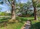 Expansive backyard featuring mature trees, a lush lawn, and a stone path leading to a stately white home at 5001 S Shore Crest Cir, Tampa, FL 33609