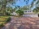 An elegant brick driveway leads to a stately white home with an attached three-car garage at 5001 S Shore Crest Cir, Tampa, FL 33609